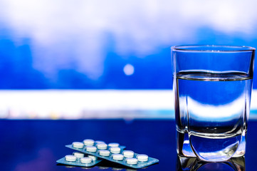 a glass of water and Two blister pack of medicines