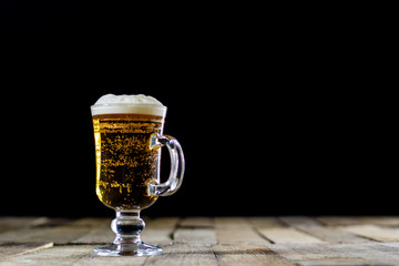 A pint of tasty beer on a wooden table. Beer in pint and beer bottles.