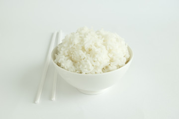 RICE BOWL AND CHOPSTICKS
Steamed rice in a white bowl served with white chopsticks on a white background. 