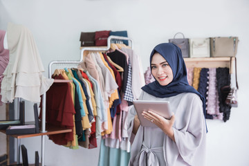 muslim woman using digital tablet in clothing store