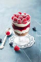 Single trifle with raspberry and blueberry in a glass on white napkin on blue background