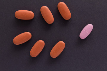 Heap of pills spreaded over color table. Group of assorted beige tablets. Black background.
