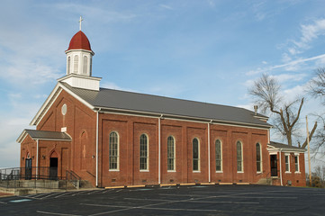Christian landscape photo of a beautiful red brick church in the countryside with a blue sky...