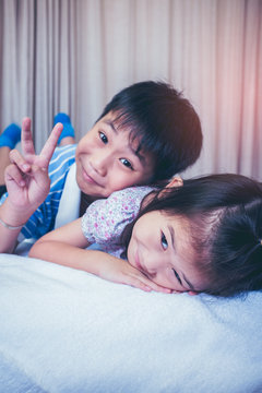 Asian siblings smiling and having fun in bedroom. Vintage tone.