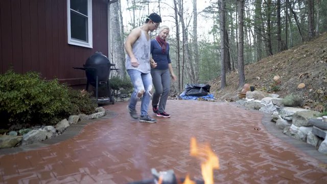 Looking through fire, a mature woman and her hip muscular teen son do a middle eastern line dance, the dabke.