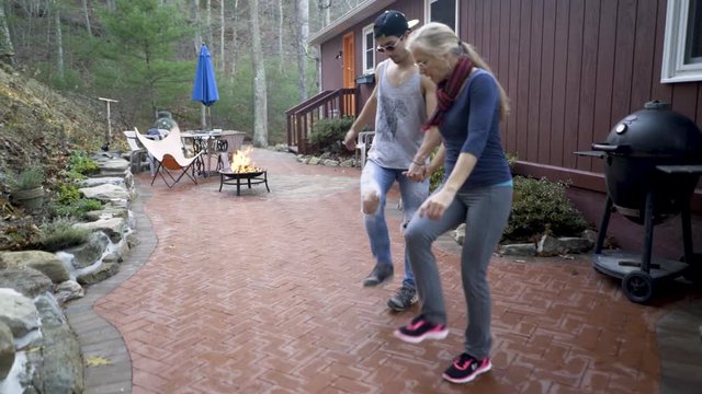 Mother and hipster teen son hold hands and do fancy footwork doing the dabke a middle eastern folk dance.