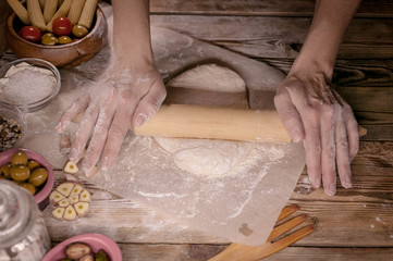Female hands cook dough for home-made pizza.
