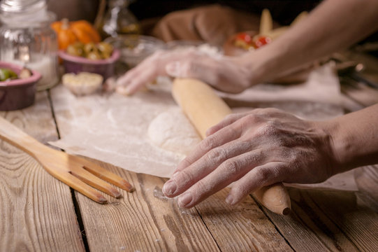 Female hands cook dough for home-made pizza.