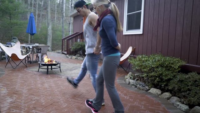 Camera moves with two dancers, a mature woman and hip teen son, as they do fancy footwork doing the dabke.