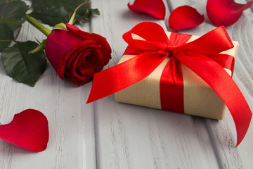Gift box,red rose and  petals on the grey  wooden background