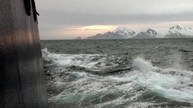 Waves from ship in ocean of Antarctica. Glacier on background of snow mountains.Travel in cold polar north. Scenic blue water. Global warming. Nature of desert . Wilderness area.