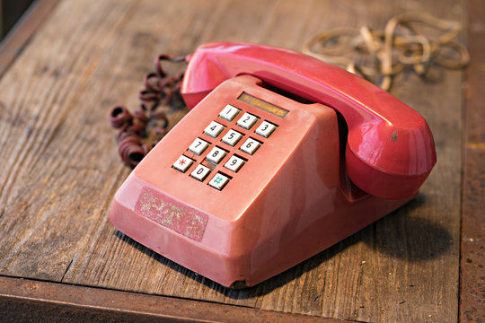 Retro red telephone on wood table.