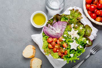 Cute green salad with mini cherry tomatoes, red onion slices and feta cheese stars. Top view copy space.

