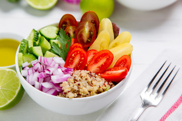 Healthy buddha quinoa salad bowl with tomatoes, cucumbers, red onions. On white wooden table background. Top view copy space.

