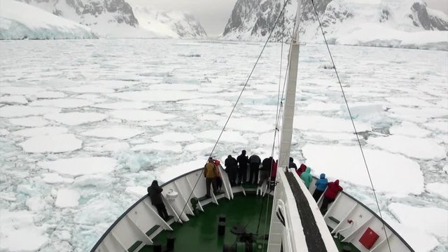 People on ship on background of ice floe in ocean of Antarctica. Travel in cold polar north. Scenic blue water. Global warming. Nature of desert . Wilderness area.