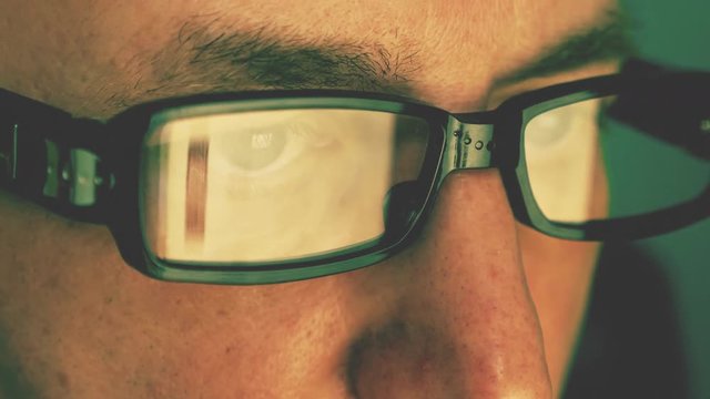 Extreme close up man face eyes glasses. Reflection from computer laptop screen in fashion glasses. Caucasian white man. Man portrait. Surfing internet concept. Sinematic film look.