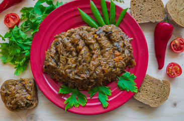 Stewed forest mushrooms cooked with onions and carrots on a red plate with bread and chili