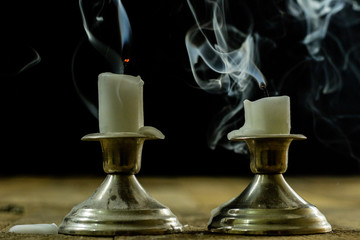 Blown candles in silver candlesticks with smoked wick. Smoke from a wick on a black background.