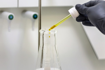Professional laboratory with a men hand dropping liquid into a galss