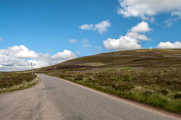 Fototapeta na wymiar Typical wavy landscape with road in central Scotland