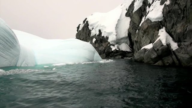 Iceberg and ice floe in ocean of Antarctica. Glacier on background of snow mountains.Travel in calm cold polar north. Scenic blue water. Global warming. Unique nature of desert . Wilderness area.
