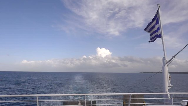 Ferry boat in Greece view on sea and waving national flag
