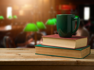 Green cup of coffee on stack of books