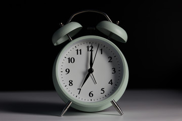 Vintage alarm clock in black background with light.