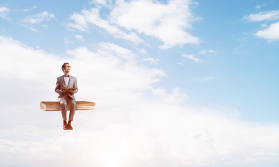 Young businessman or student floating in blue sky and studying the science