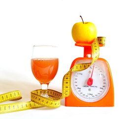 measuring tape, kitchen scale, a cup of freshly squeezed orange juice and yellow apple isolated on...
