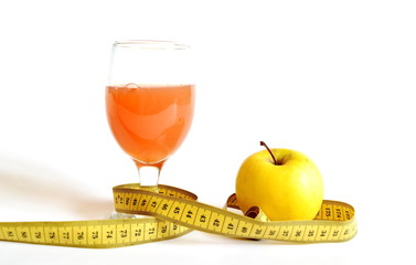 measuring tape, a glass of freshly squeezed orange juice and yellow apple isolated on white...