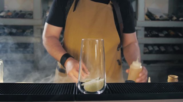 The bartender making cocktail Mojito in a nightclub bar, shot with smoke machine, professional modern bar