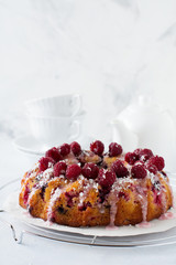  Lemon bundt-cake with raspberries on a light background. Selective focus.