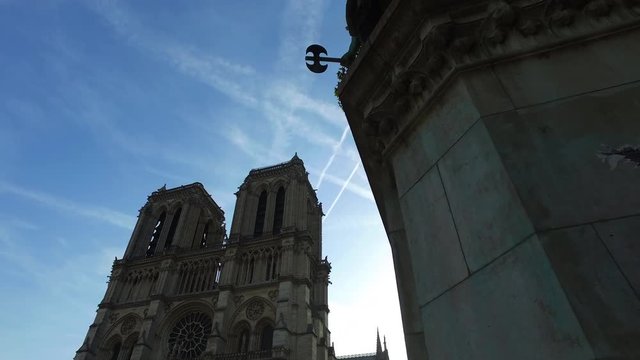 The Notre Dame in Paris in a moving camera shot with streetlights and trees in the front.