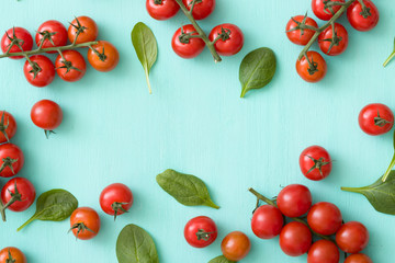 Top view on bunches of cherry tomatoes with basil leaves on turquoise wooden background. Healthy food.