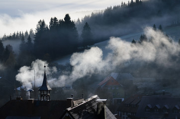 Fototapeta na wymiar Smoke rising over a village in the Black Forest in the morning