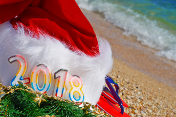 Santa Claus hat and toys оn sand. 2018