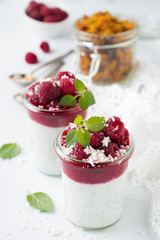 Layered raspberry smoothies with chia seeds, fresh raspberry and coconut on a light stone background. Useful dessert. Selective focus.