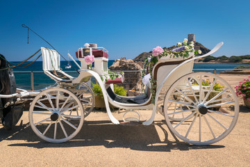 Old white wooden carriage during a wedding on the sea.