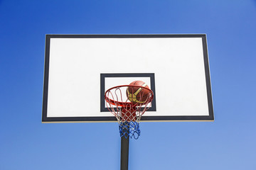 Basketball ball hit the basket in the blue sky background