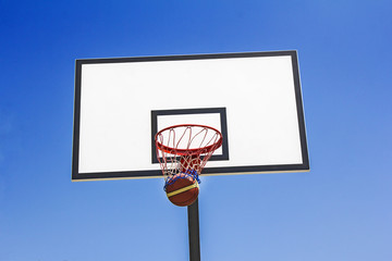 Basketball ball hit the basket in the blue sky background