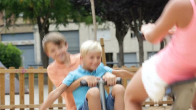 Cheerful children are teetering on the swing on the playground.
