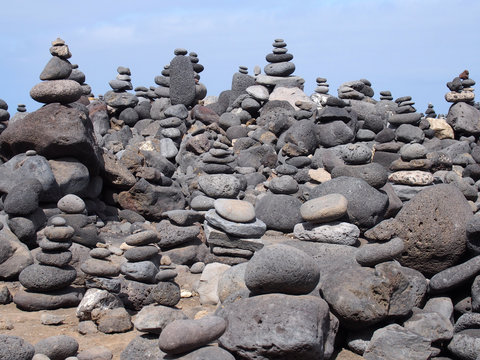 large towers of stacked pebbles on a beach with blue sky