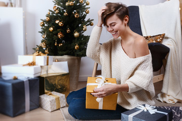 Young woman is preparing presents for the xmas and new year. The photo is made in a holiday interior