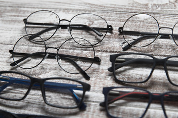 Six eyeglasses on a light wooden background