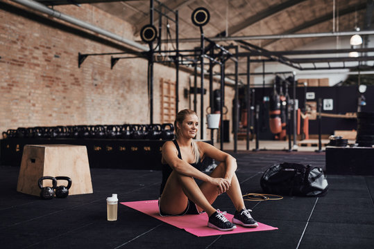 Smiling Young Woman Sitting In A Gym After Working Out