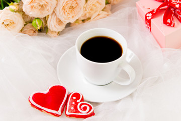 Valentine's day. Wedding, mother's day. A Cup of coffee and two gingerbread heart on a background of flowers and gifts.