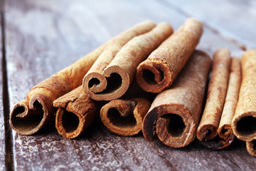 Ground cinnamon, cinnamon sticks, on old wooden background in rustic style.