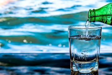 Pouring water into a glass against the nature landscape