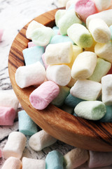 Colorful mini marshmallows on wooden background in bowl.